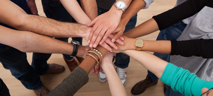 Diverse people stacking hands together.