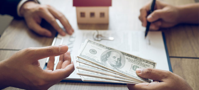 Man signing financial documents and handing large amount of money to another man. Mortgage concept.